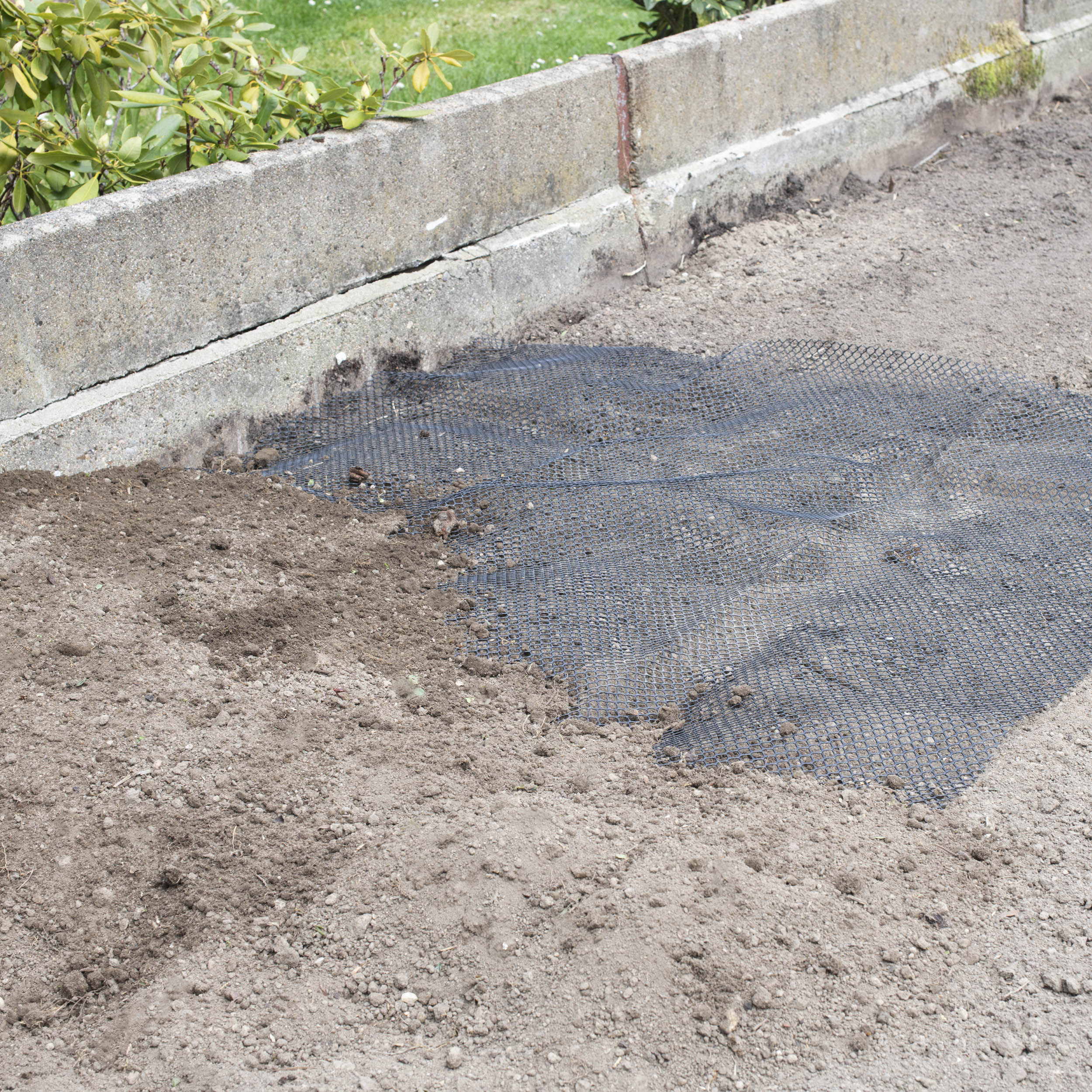 Das Maulwurfgitter wird unter dem Rasen verlegt.